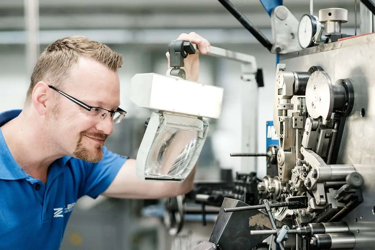 Mitarbeiter prüft eine Feder auf ihre Festigkeit und Funktionalität im Testbereich.