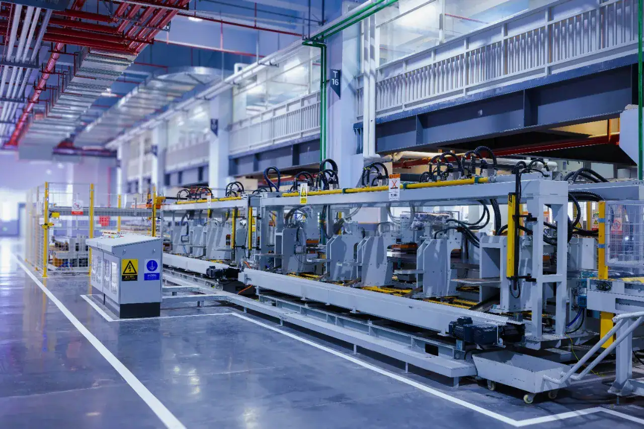 Linea di produzione automatizzata in uno stabilimento industriale con pavimento in resina grigia e segnaletica di sicurezza, ambiente conforme ai requisiti ESD