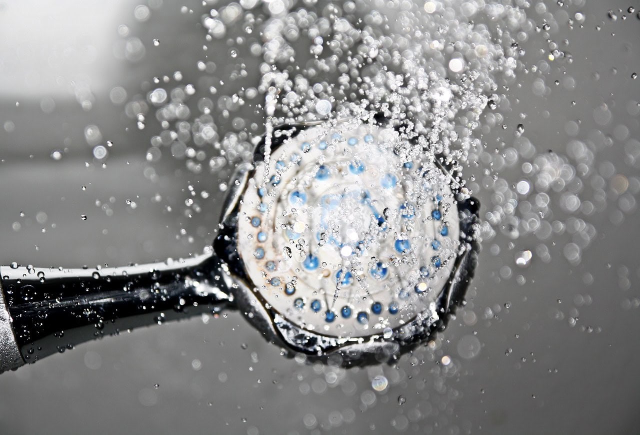 Shower head water cascading downwards from above.