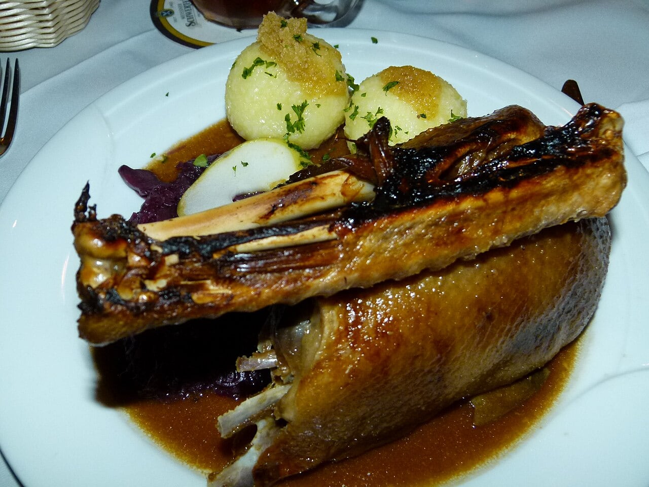 Gänsekeule mit Apfelrotkohl und Klößen auf einem Teller