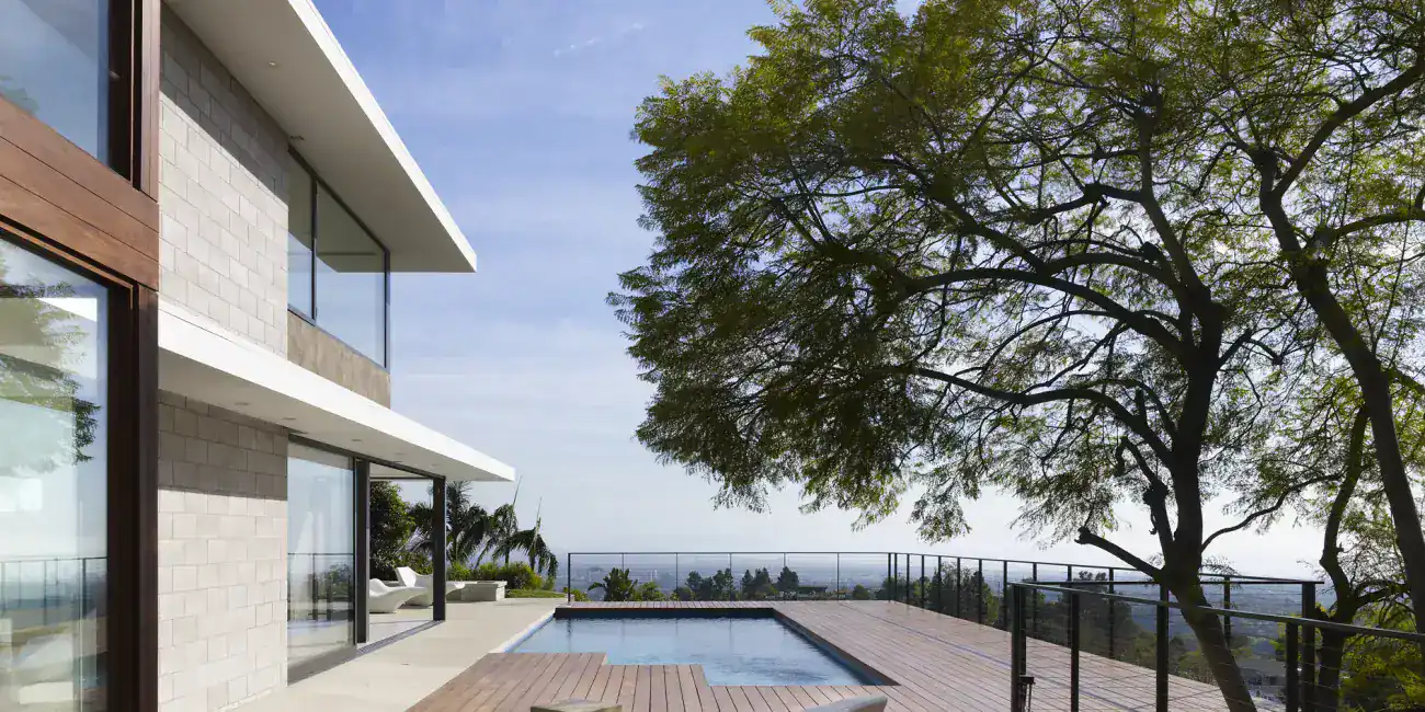 Modern house exterior with a pool and wooden deck, featuring clean lines, large glass windows, and minimalist furniture.
