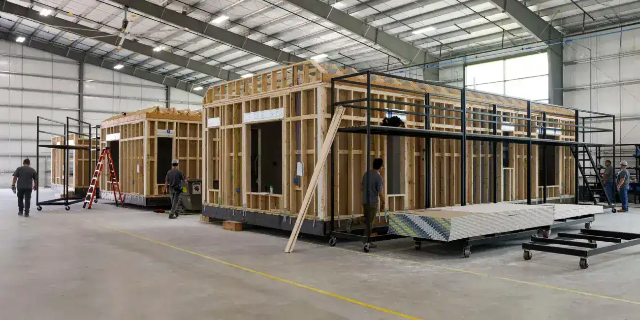 Wooden building framework with steel scaffolding in an industrial warehouse.