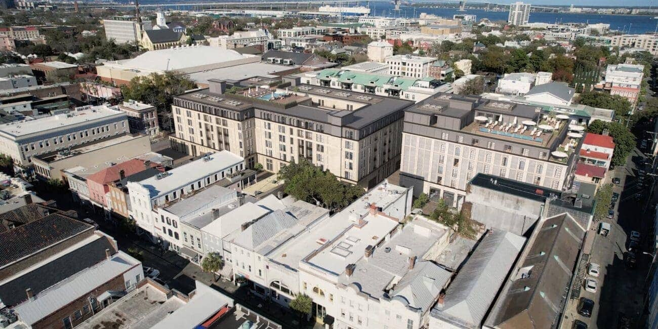Modern mixed-use building with rooftop terraces, featuring a blend of classic and contemporary architecture, located in an urban setting with a bridge in the background.