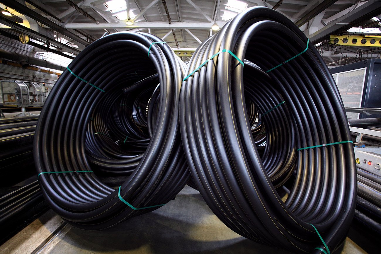 Large coils of black plastic tubing stacked indoors.