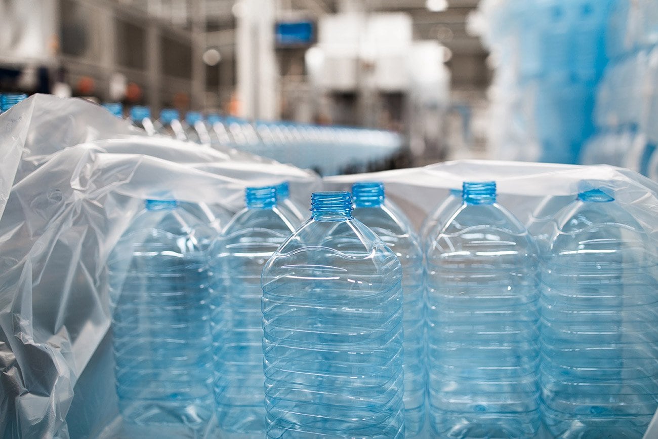 Rows of clear plastic water bottles with blue caps.