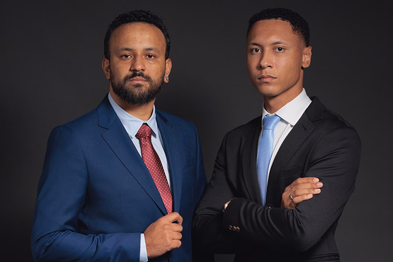 Jhonatan Lima e João Igor, advogados criminalistas, de terno, lado a lado, em retrato corporativo no estúdio em BH
