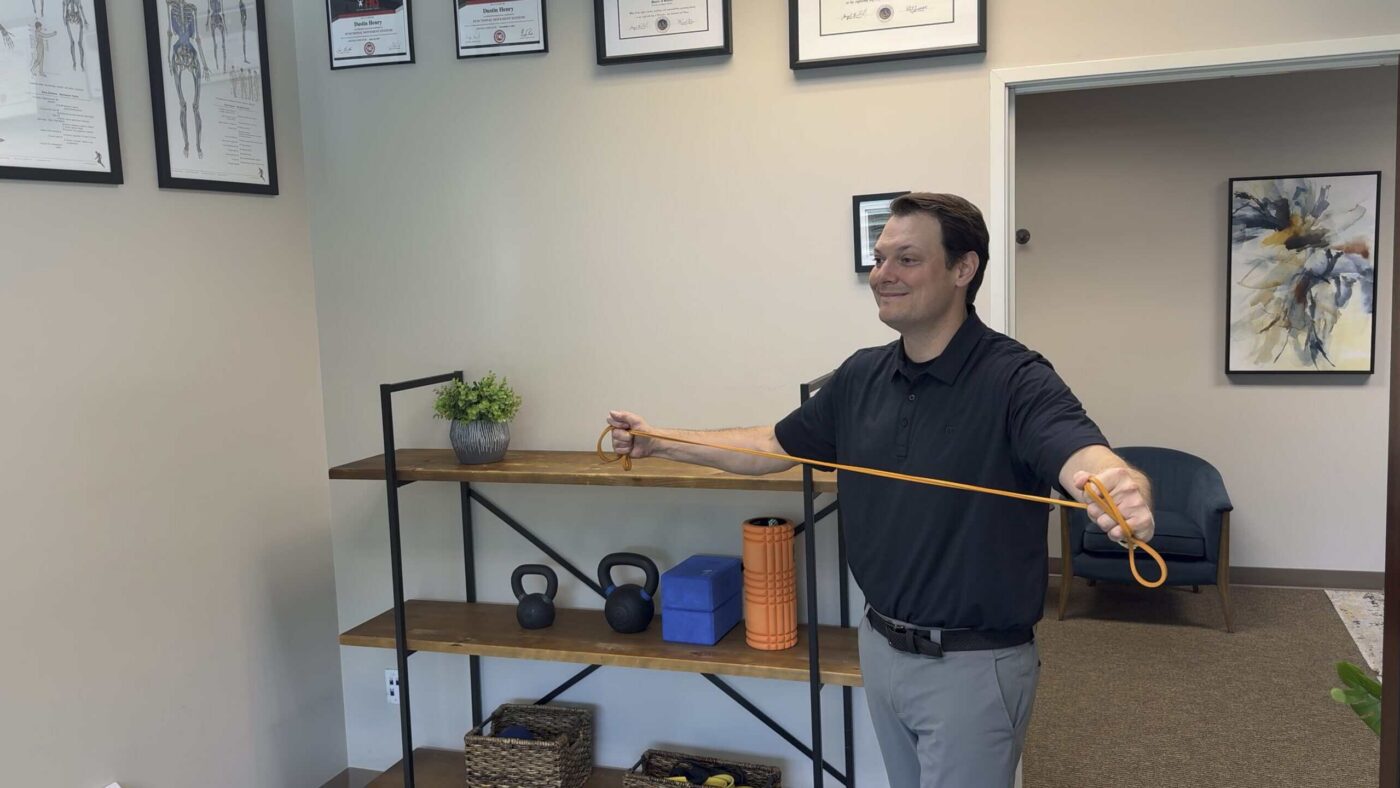 Dr. Henry demonstrating a resistance-band shoulder exercise at Victory Spine and Sport