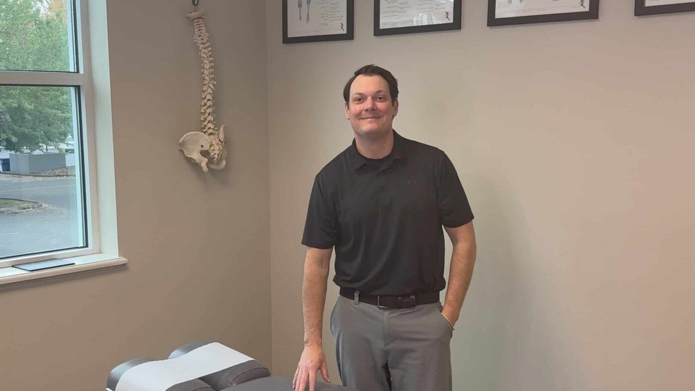 Dr. Henry standing beside a chiropractic treatment table at Victory Spine and Sport in Vancouver, WA.