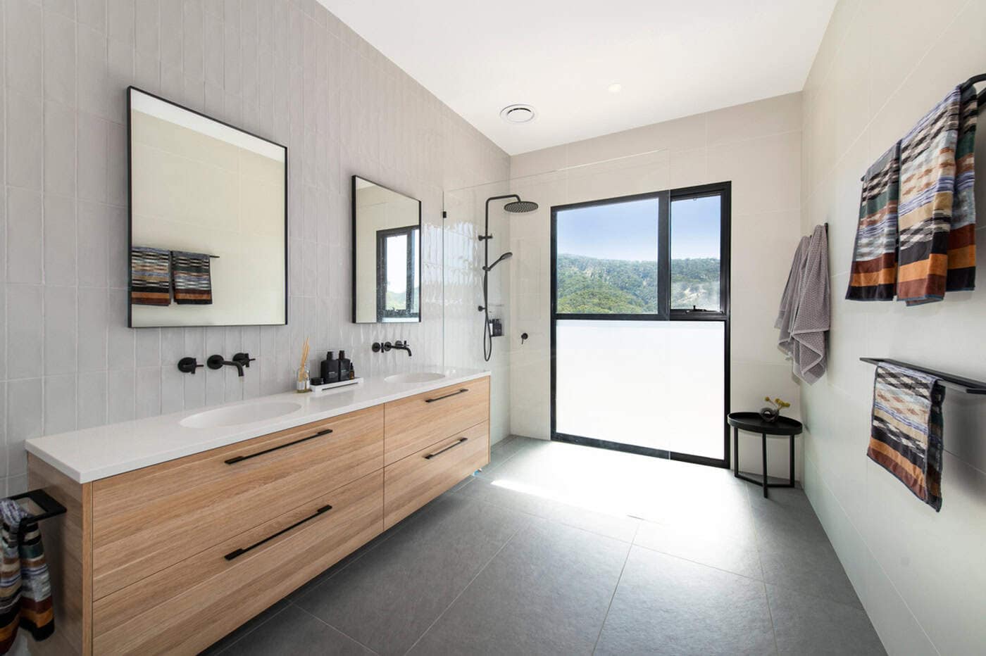Modern bathroom with a double timber vanity, black matte hardware, dual mirrors, and a walk-in shower.