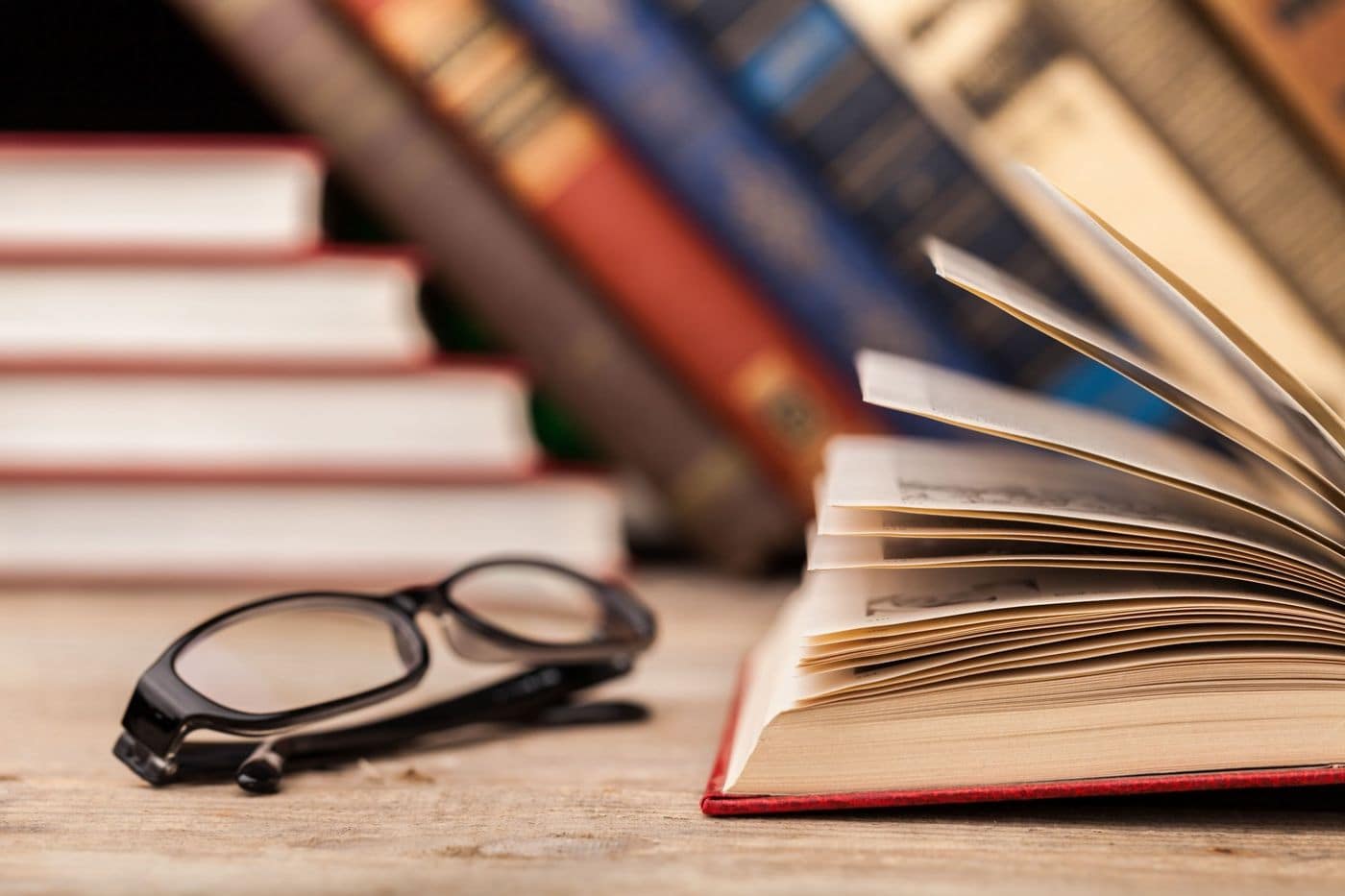 Foto de um livro aberto e um óculos ao lado