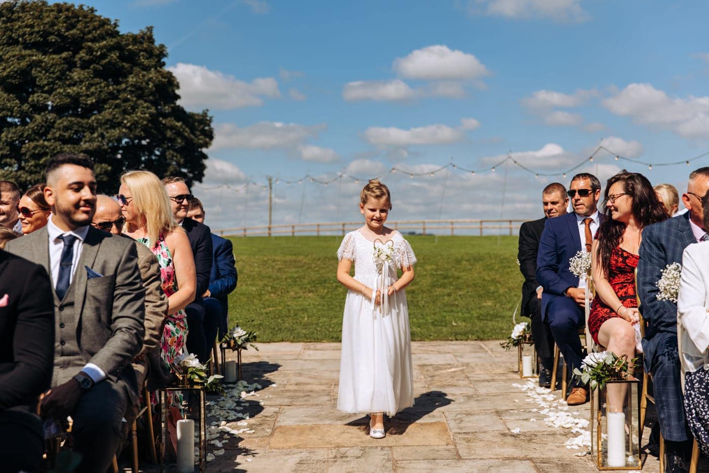 an outdoor ceremony with the bride walking down the aisle to get married at heaton house farm