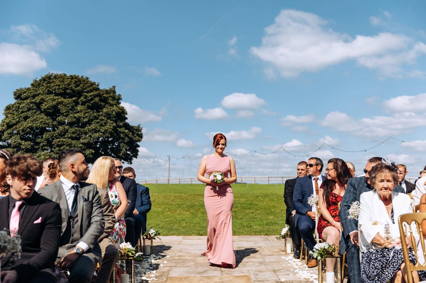 an outdoor ceremony with the bride walking down the aisle to get married at heaton house farm