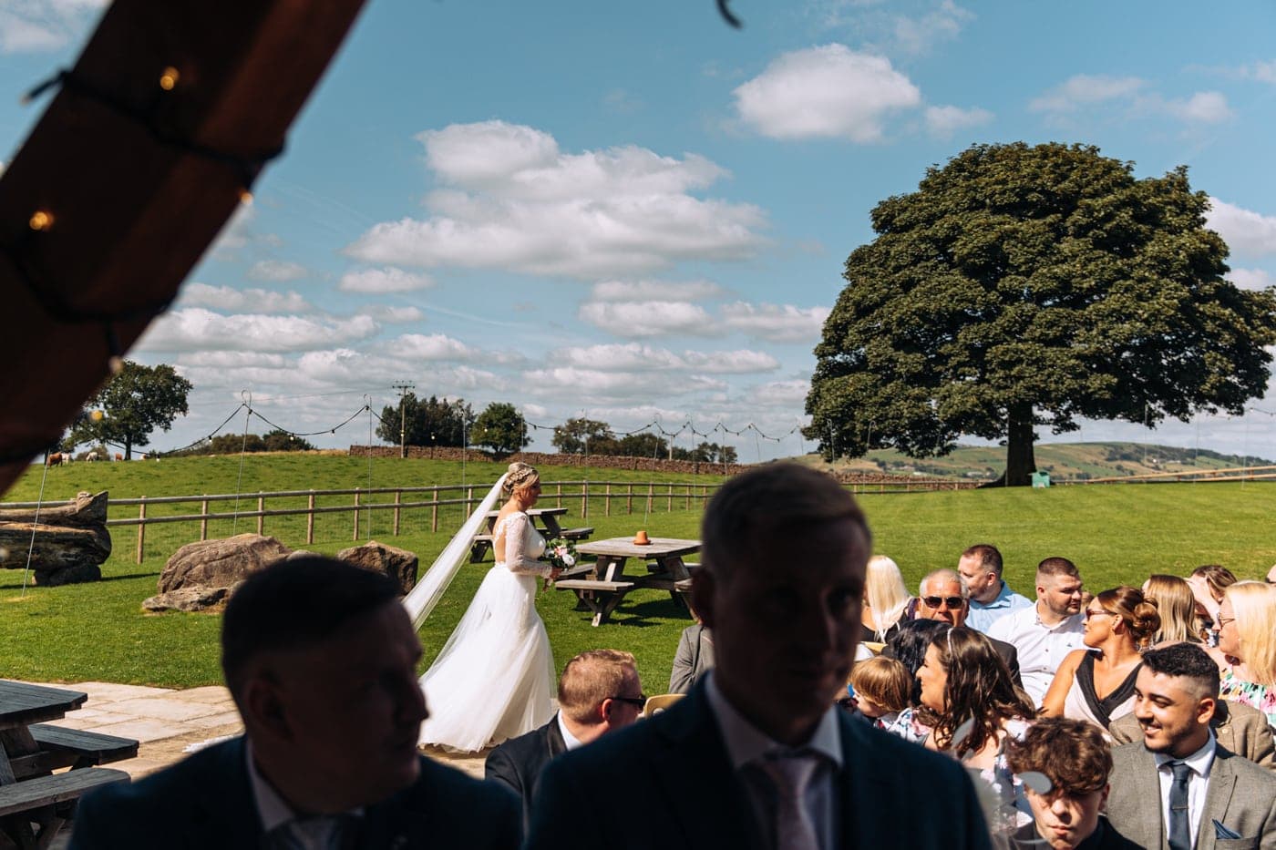 an outdoor ceremony with the bride walking down the aisle to get married at heaton house farm