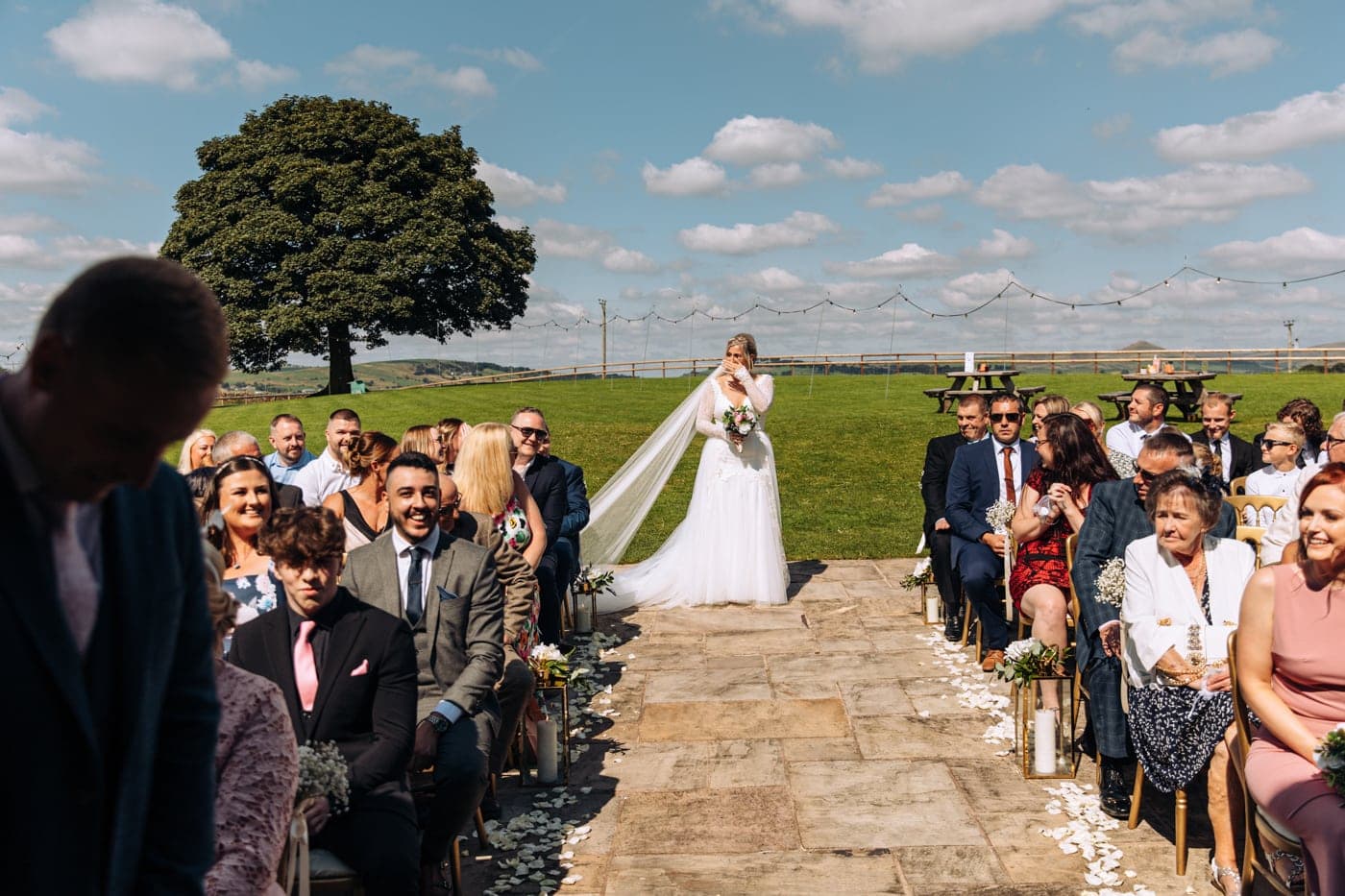 an outdoor ceremony with the bride walking down the aisle to get married at heaton house farm