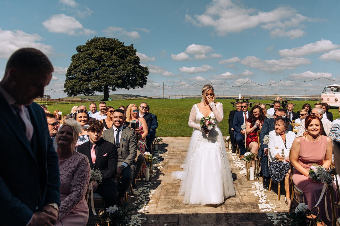 an outdoor ceremony with the bride walking down the aisle to get married at heaton house farm