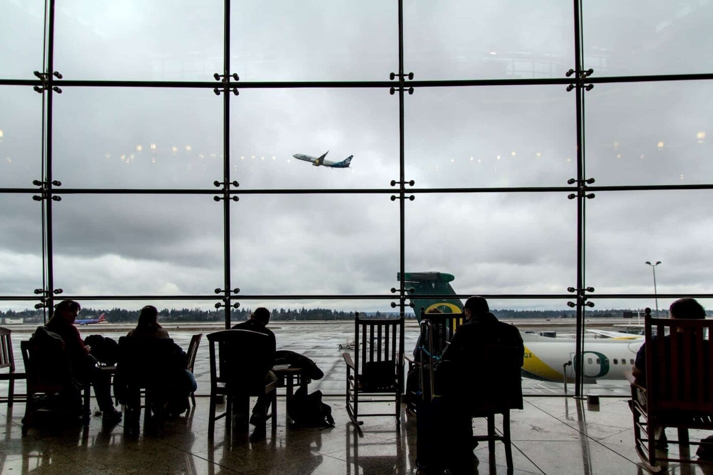 Airport window views with passengers walking through the terminal.