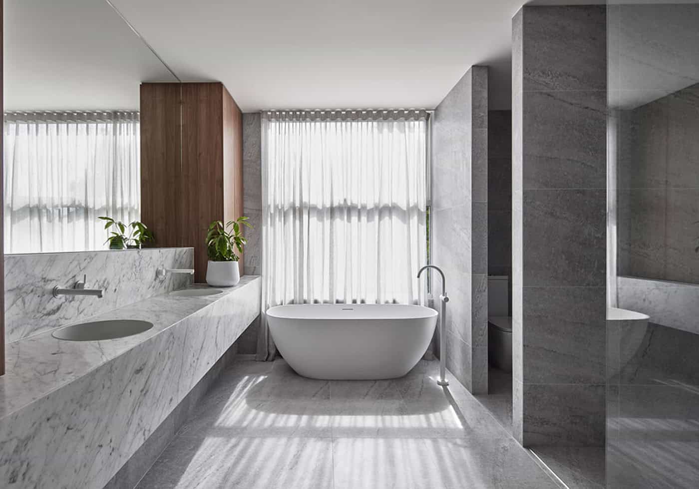Luxurious bathroom with a freestanding oval bathtub, grey stone tiles, and a floating marble double vanity.