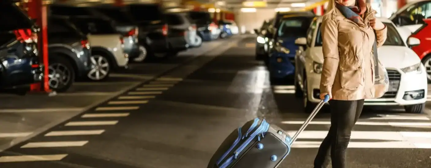 Traveler pulling suitcase through parking garage at airport