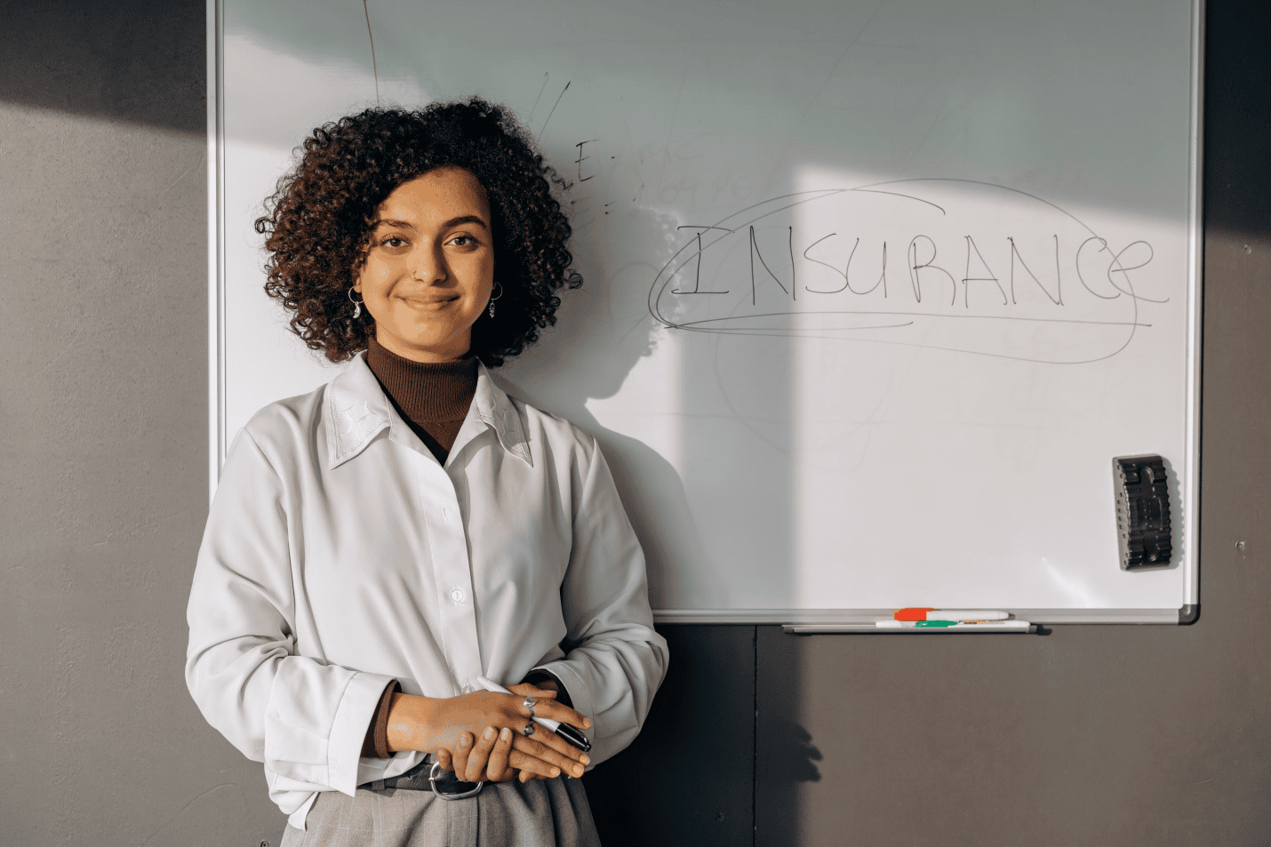 Woman standing near a white board which says insurance