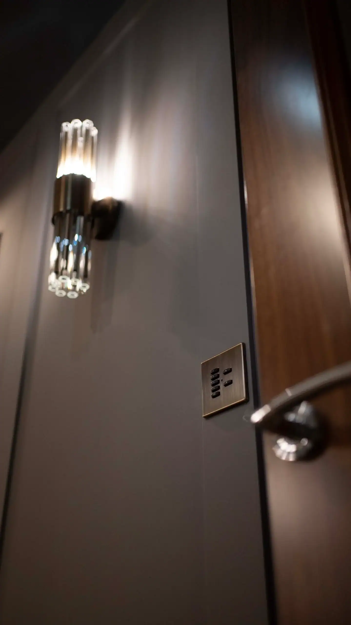 Wall light and a lighting keypad beside a wooden door in a games room