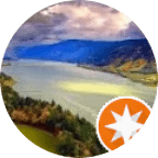 A wide river flows between green hills under a cloudy sky, with sunlight breaking through the clouds. An orange star badge overlaps the lower right corner.