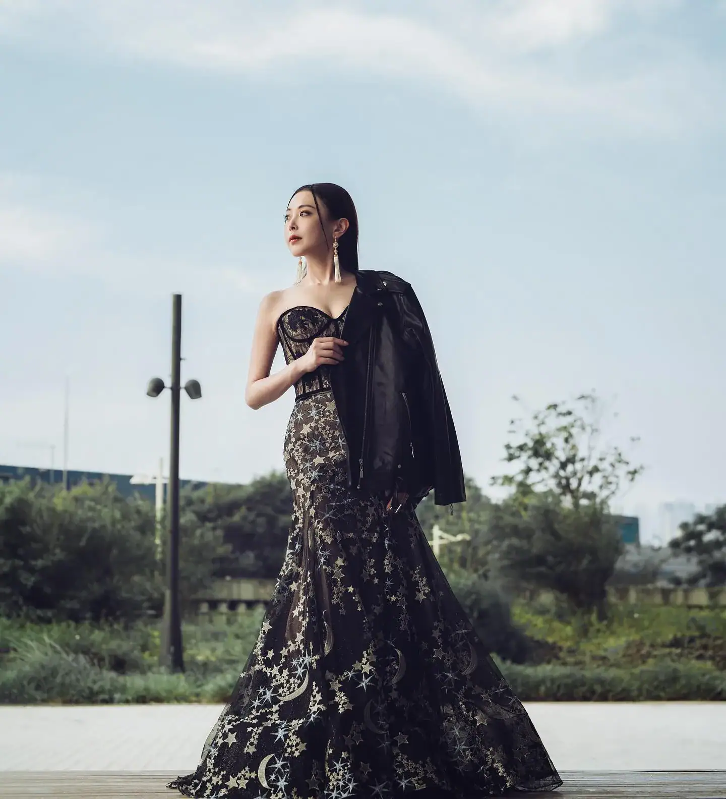首頁 17 時尚新娘外景婚照:藝人 Hebe 陳婉婷身穿精緻的黑色蕾絲魚尾晚裝,手拿皮衣,在極簡幾何建築背景前展現高冷名模氣場,適合追求獨特風格的香港新娘。