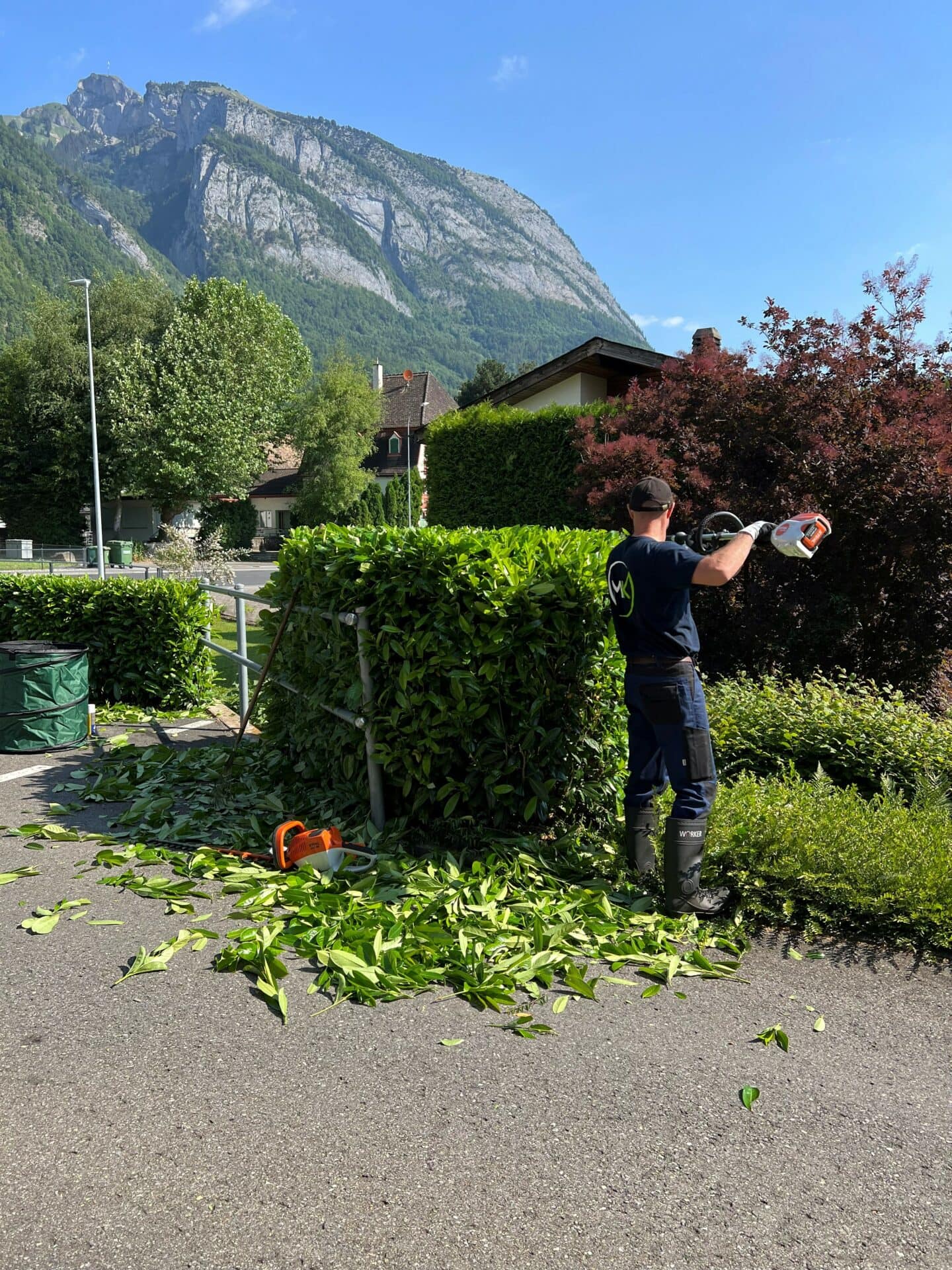 Hauswartung Mitarbeiter am Heckenschneiden
