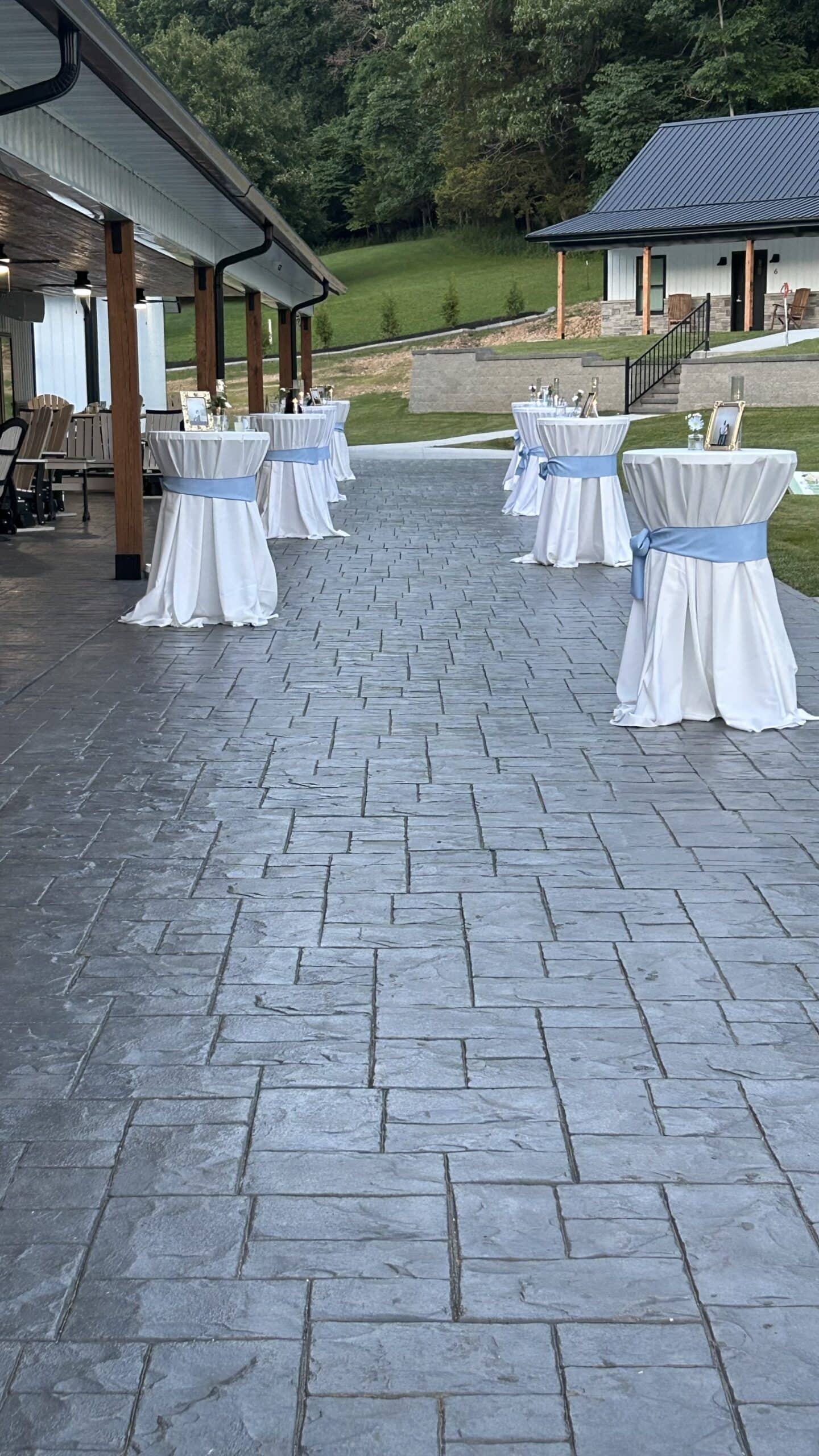 Outdoor covered patio with round cocktail tables set with white linens at Romaine Valley Weddings & Events