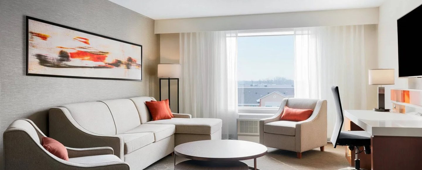 A luxury hotel room designed by a hospitality renovation company to include low-profile furniture and burnt orange accent pillows