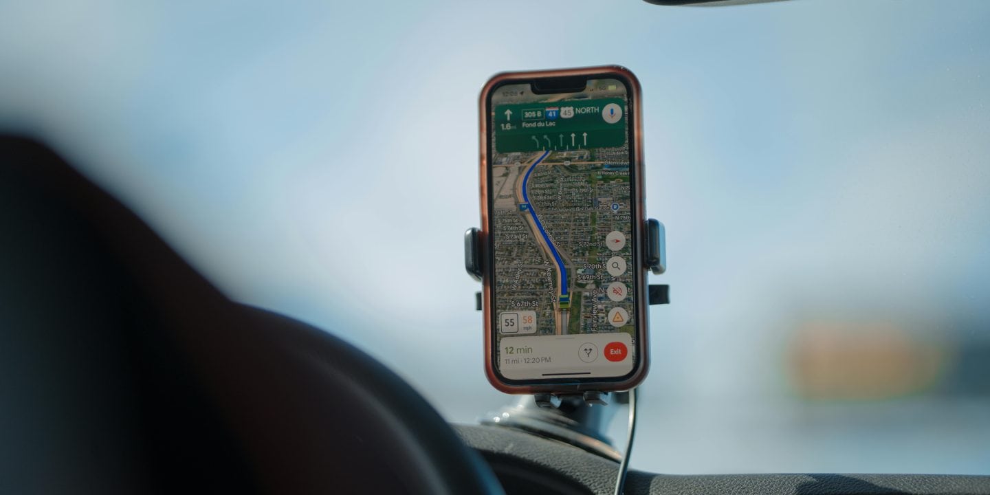 A smartphone screen displaying various travel apps with a scenic road trip background, highlighting apps for navigation, accommodation, and entertainment.