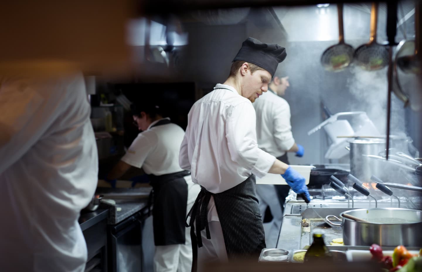 Chefs in a bustling commercial kitchen skillfully preparing various dishes with fresh ingredients and professional equipment