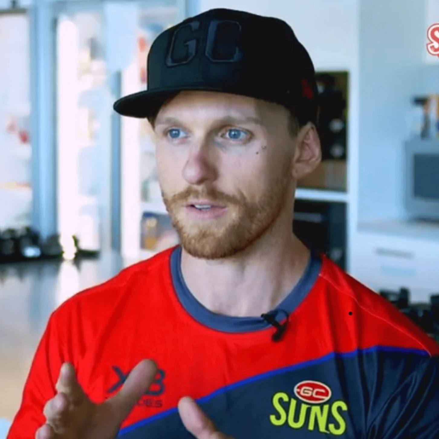 A man in a GC SUNS cap and sports attire speaking during an interview.