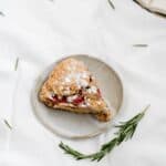 Overhead shot of a slice of vegan strawberry rosemary scone on a plate.