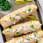 Elote with feta, cilantro, and lime wedges.