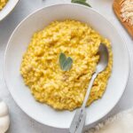 Pumpkin risotto in a serving bowl with a spoon.