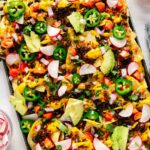 A sheet pan full of nachos that are vegan with all of the toppings.