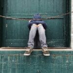 顔を隠して座り込む少年