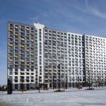 Фрагмент жилого дома в ЖК Новый Зеленоград с благоустроенным тротуаром и припаркованными автомобилями.