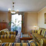 Evening ambiance in a hotel suite living room, professionally captured by Kirill Toll. The warm lighting and cozy arrangement of sofas create a welcoming mood, showcasing the photographer's skill in setting the scene for hospitality.