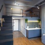 Двухуровневый лофт в ЖК Loftec со спальней на антресоли, чёрной металлической лестницей, серой кухней со стеклоблоками и трековым потолочным освещением — съёмка Кирилла Толль