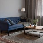 Интерьер гостиной с синим диваном Chesterfield, лофт-столиком, серыми шторами и классическим ковром. Ленинградский проспект, Москва.