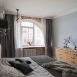 Интерьер спальни в стиле лофт: деревянный комод, кровать и арочное окно с кирпичной кладкой. Ленинградский проспект, Москва.