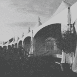 A row of outdoor event vendor tents set up at a bustling event, showcasing various services and products for attendees.
