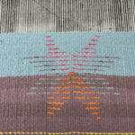 a woven piece on the loom featuring a star