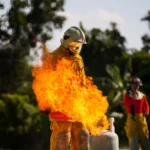bombeiro com equipamento treinando com um botijão de gás.