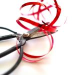 A detailed image of antique scissors with red ribbon on a white surface.