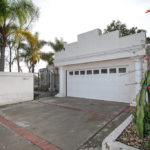 White Mission-style home with a stepped parapet roofline, a two-car garage with decorative columns, and drought-tolerant landscaping at 2823 Vancouver Ave in North Park.