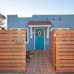 Street-facing view of 3764 Alabama in North Park featuring a horizontal wood fence with a silver mailbox and house numbers, a terracotta tile path, and a blue bungalow with a teal front door.