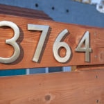 Modern silver house numbers "3764" mounted on a horizontal wood fence at a North Park home on Alabama Street.