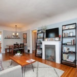 Cozy living room at 3764 Alabama in North Park featuring a modern fireplace, black ladder bookshelves, a wood coffee table with hairpin legs, and a view into the adjacent dining area.